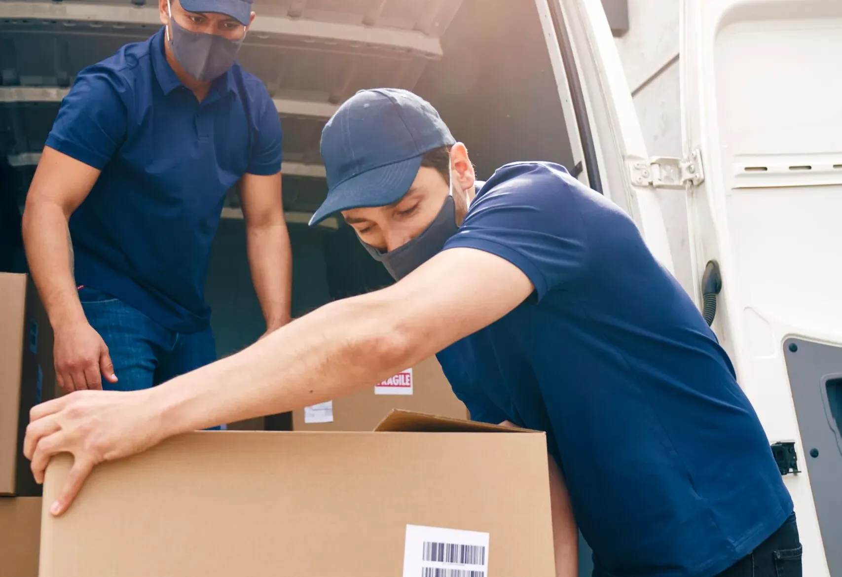 Two Couriers In Protective Masks Unloading Package